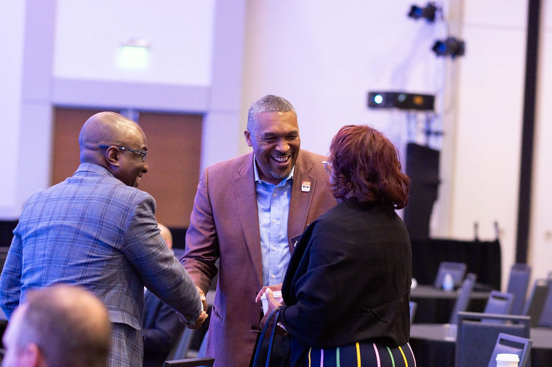 Attendees greeting each other in the ballroom at ADIC 2026