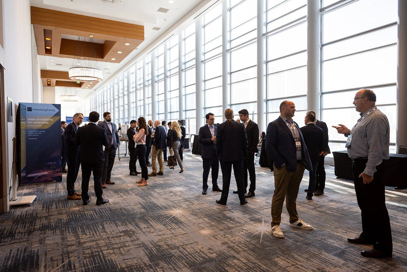 Attendees networking along the window-lined foyer at ADIC 2026