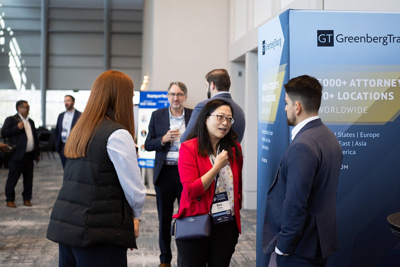 Attendees networking beside an exhibitor display at ADIC 2026